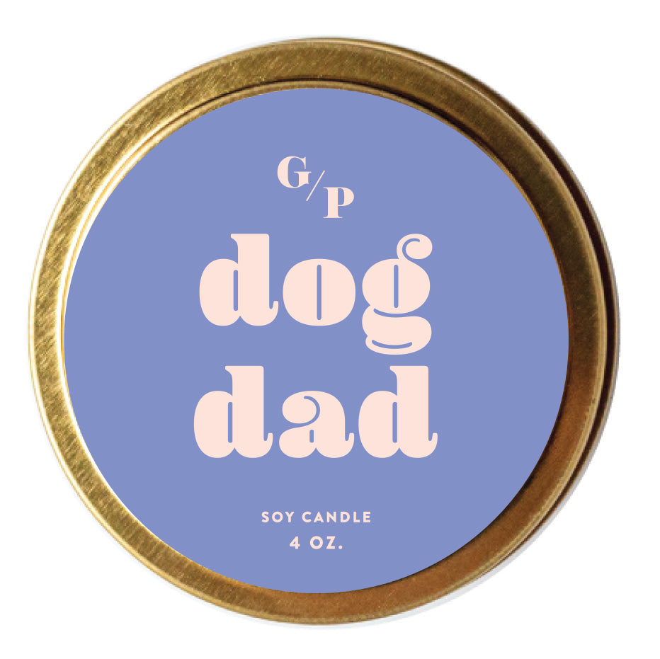 Top view of purple candle tin lid with 'dog dad' text and gold rim.