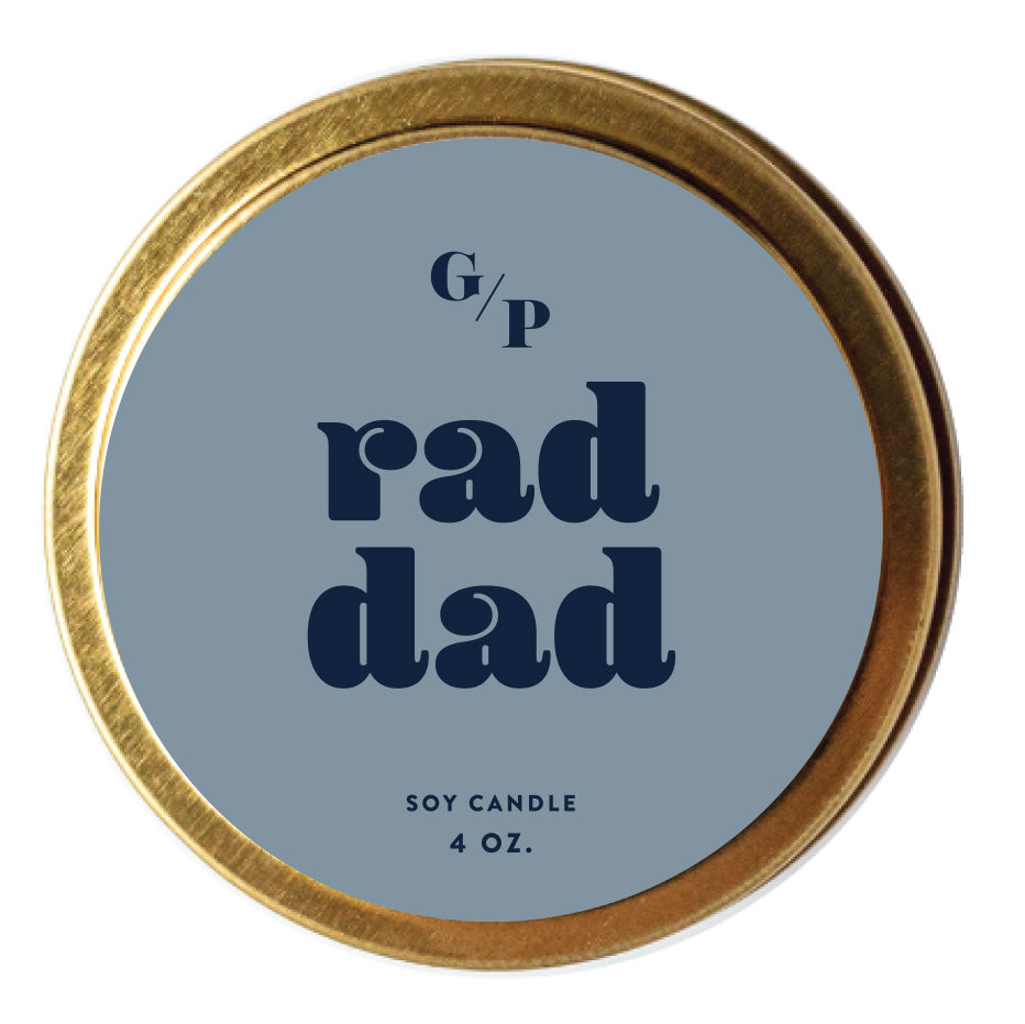 Top view of deep blue candle tin lid with 'rad dad' text and gold rim.
